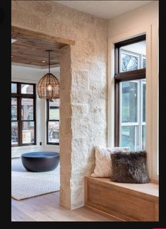 the interior of a home with stone walls and wood flooring, large windows, and a bench