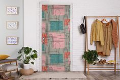 an open door in a white room with clothes hanging on the rack and a potted plant next to it