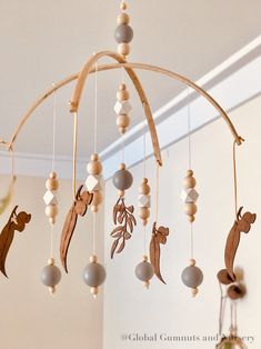 a mobile made out of wood and beads with animals hanging from it's sides