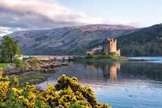 a castle sitting on top of a lake surrounded by mountains