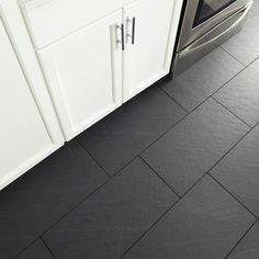 a kitchen with black tile flooring and white cabinets