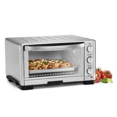 an open toaster oven with food in it and tomatoes on the counter next to it