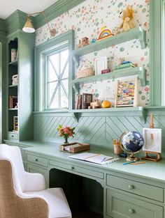 a green desk and chair in a room with floral wallpaper on the walls behind it