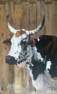 a cow painted on the side of a wooden fence