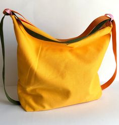 Comfortable, roomy, soft, beautiful, practical and versatile. A bag that easily goes from bag to backpack and vice versa. An ideal backpack bag for all seasons and all occasions, traveling, on holiday, at the seaside, in the mountains, for the office, for the gym, etc It is made of yellow cotton canvas, and lined in white cotton fabric, it has a large internal pocket and is closed by a green zip. The straps are made of cotton: one orange and the other sage green. Made by hand. I put my heart, pa Fabric Backpack, Yellow Backpack, Anti Theft Backpack, Handmade Belts, Novelty Bags, The Seaside, Backpack Bag, On Holiday, Summer Crafts