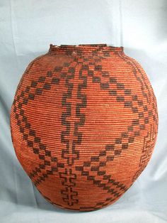 an orange and black woven basket on a white cloth covered background with lines in the middle