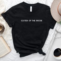 a black t - shirt with the word groomsllay printed on it next to an open book