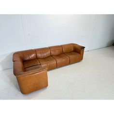 a brown leather couch sitting on top of a white floor