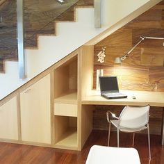 a laptop computer sitting on top of a desk next to a stair case in a room