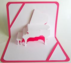 a pink and white card with an image of a grand piano on it's side