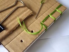 a pair of scissors sitting on top of a piece of brown paper with green ribbon