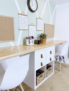 a white desk with two chairs and a clock on the wall above it in a home office