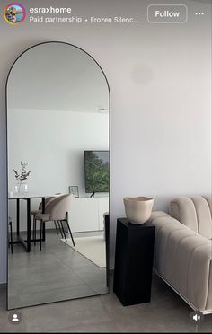 a living room filled with furniture and a large mirror on the wall next to a couch