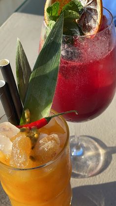 two glasses filled with drinks sitting on top of a table