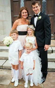 a couple and their children are posing for a photo outside the church with flowers in their hair