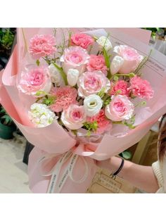 a woman holding a bouquet of pink and white flowers