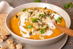 a white bowl filled with carrot soup next to crackers