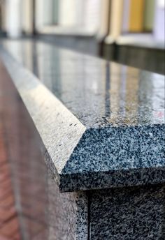 a close up view of the top of a granite bench with red brick flooring