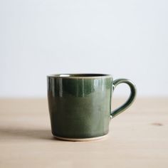 a green cup sitting on top of a wooden table