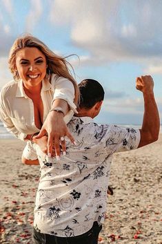 a woman holding onto a man on the beach