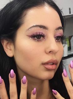 a woman with pink nail polish holding her hands up in front of her face and looking at the camera