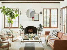 a living room with couches, chairs and a fire place in the center area