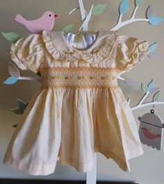 "This baby girl dress hand smocked in shades of yellow and hand embroidered with matching bullions on the bodice. Dress is fully lined in cotton fabric. Ruffled Short puff sleeves and Peter Pan collar have  embroidered with matching flower details. The back closes with tie back sashes and zip. This beautiful dress could be used as a flower girl dress. Material Outer : Cotton Material Inner : Cotton Cold gentle hand wash Available sizes Size 3-6 months (AU 00) Length 14\" Chest circumference 20\" Yellow Baptism Dress For Summer, Yellow Summer Dress For Baptism, Yellow Smocked Fitted Dress, Yellow Fitted Smock Dress, Fitted Yellow Smock Dress, Fitted Smock Yellow Dress, Yellow Cotton Smock Dress, Yellow Ruffled Dress For Baptism, Yellow Ruffle Dress For Baptism