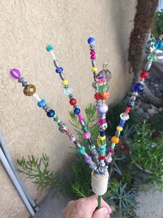 a person is holding a small tree made out of beaded beads and glass beads