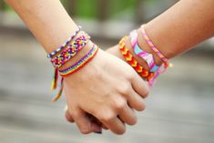 two people holding hands while wearing colorful bracelets