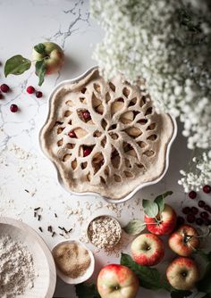 an apple pie sitting on top of a table next to other apples and spices in bowls