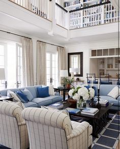 a living room with couches, chairs and tables in front of a stair case