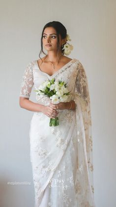 a woman in a white sari holding flowers