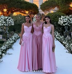 three women in long pink dresses standing next to each other on a white carpeted walkway