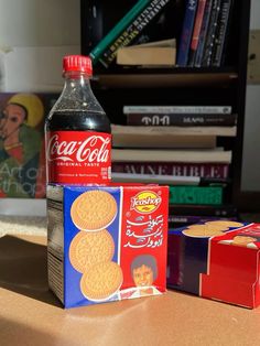 a bottle of coca cola next to two boxes of cookies and a box of candy