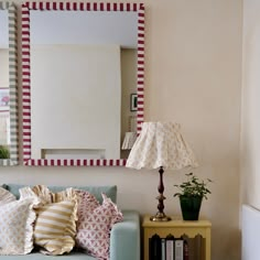 a living room with a couch, mirror and lamp on the side table in front of it