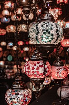 many colorful lights hanging from the ceiling in a room filled with other lamps and chandeliers