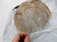 a hand is holding up a piece of bread in plastic wrap on top of a white surface