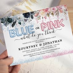 a person holding up a pink and blue party card with flowers on it's side