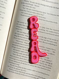 an open book with a red plastic brooch on it's cover and the word boooo spelled in cursive writing