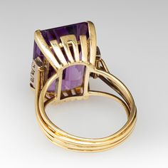 This stunning ring is centered with one (1) emerald cut natural amethyst set into a four-prong setting. The center stone is flanked to each side with a row of three (3) prong set, round brilliant cut diamonds. The ring measures 18.2mm at the top, rises 10.2mm above the finger, tapering to 4.0mm wide and 1.5mm thick at the base of the shank. It is currently a size 7.5. Cocktail Diamond Ring, Amethyst Set, Diamond Cocktail Rings, October Birth Stone, Amethyst Ring, Round Brilliant Cut Diamond, High Quality Jewelry, Round Brilliant Cut, Brilliant Cut Diamond