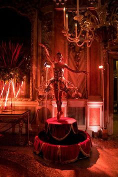 a statue stands in front of a chandelier with red lights on the walls