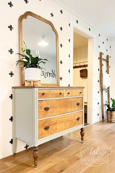 a dresser and mirror in a room with black crosses painted on the wall behind it