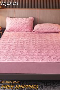 there is a bed with pink sheets and pillows on top of it, next to a night stand