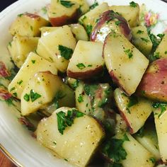 a white plate topped with potatoes covered in sauce and garnished with parsley