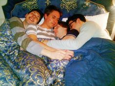 a group of people laying on top of each other in a bed with blue sheets