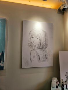 a drawing is hanging on the wall next to two pictures and a light above it