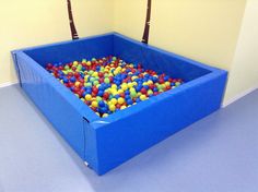 a large blue box filled with lots of colorful balls in it's center area