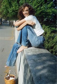 a woman sitting on top of a cement wall next to a basket