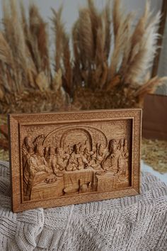 an intricate carved wooden plaque depicting the last supper of jesus, with wheat stalks in the background