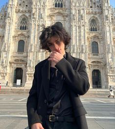 a man standing in front of a tall building with a clock on it's face